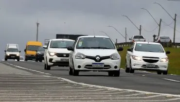 Imagem mostra três carros brancos circulado em uma rodovia,