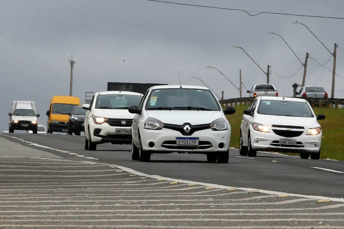 Imagem mostra três carros brancos circulado em uma rodovia,