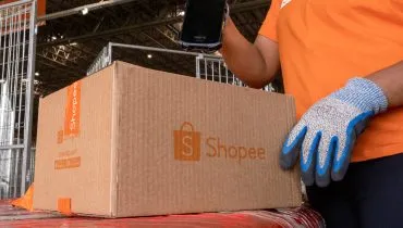 Imagem de uma caixa sendo embalada com a logo da Shopee estampada no papelão