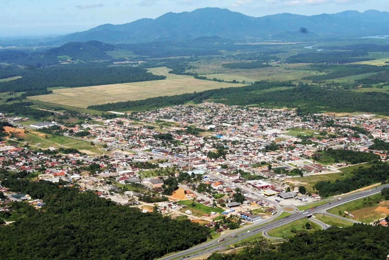 Imagem da vista aérea da cidade de Garuva, com Serra do Mar ao fundo.