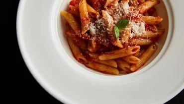 Imagem mostra um prato branco com uma bela macarronada.