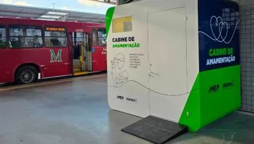 Imagem mostra um ônibus parado dentro do terminal de São José ao fundo. No primeiro plano, uma grande caixa com porta chamada cabine de amamentação