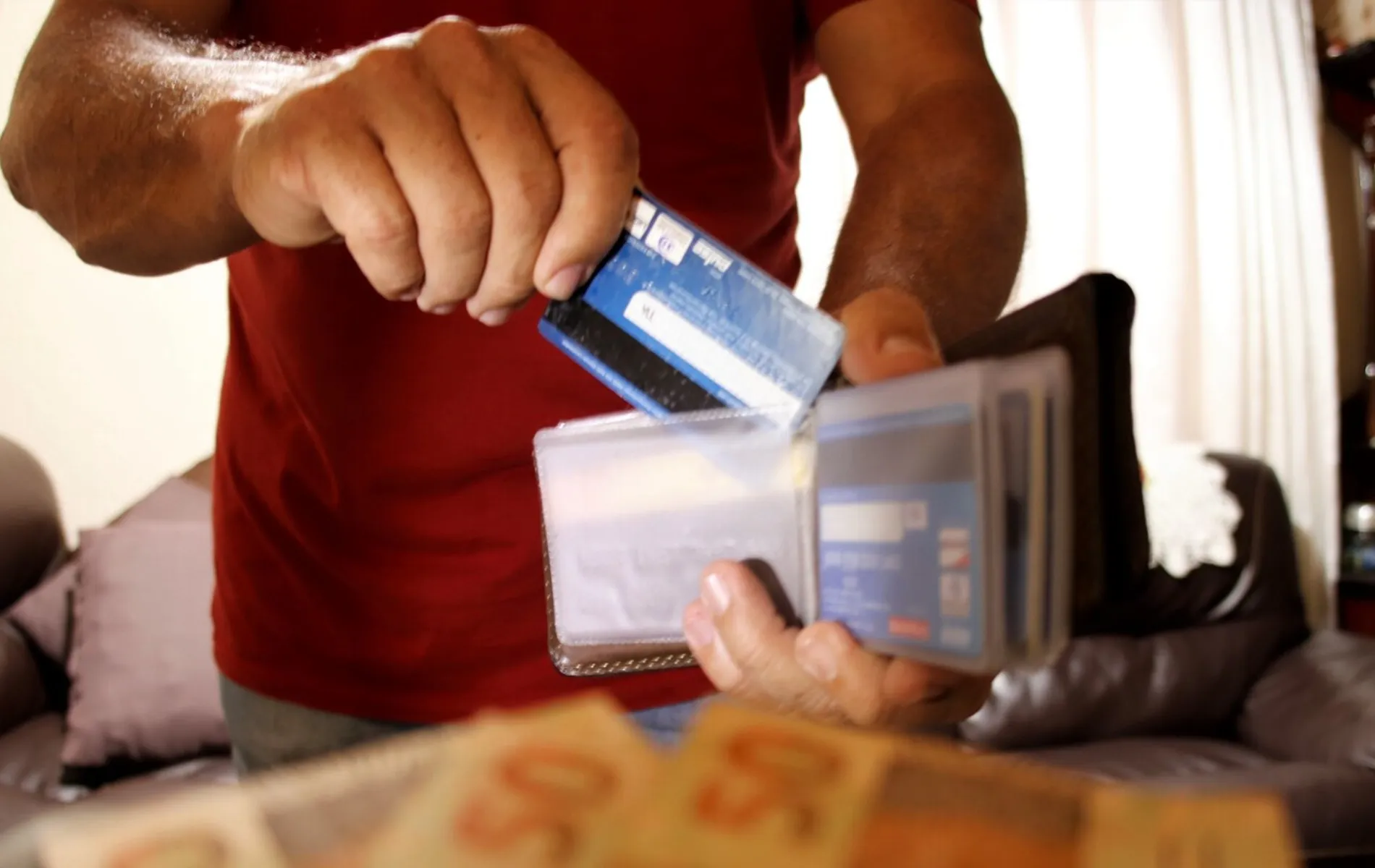 Homem segurando a carteira com cartões de crédito.