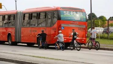 Adolescentes de bicicleta pegando rabeira em biarticulado.