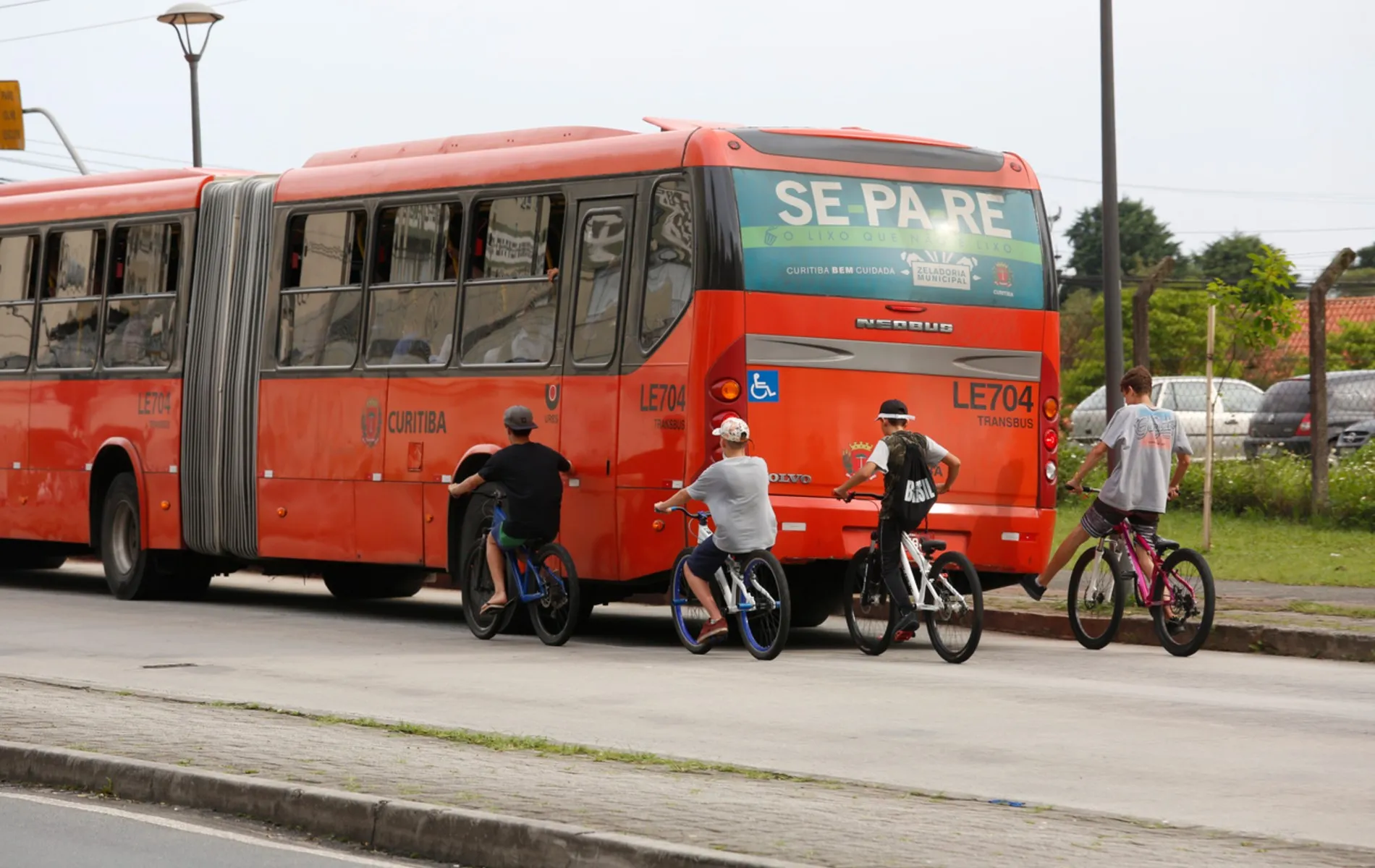 Adolescentes de bicicleta pegando rabeira em biarticulado.