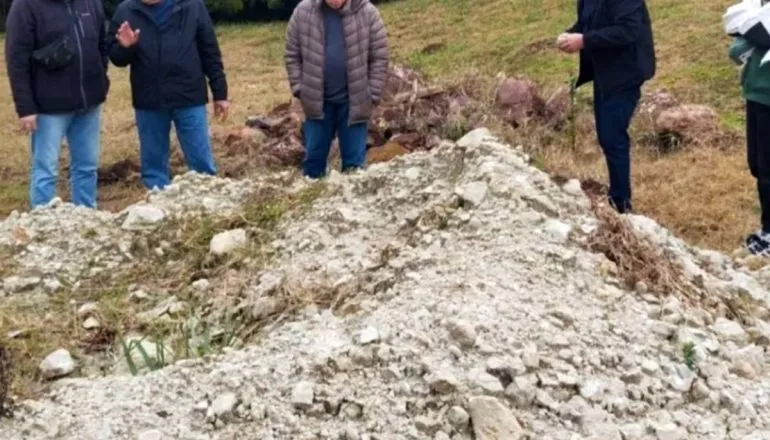 Imagem mostra homens olhando para um monte de pedra e areia.