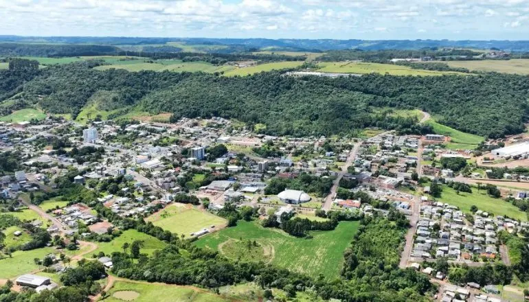Imagem aérea mostra uma cidade com muita área verde e poucos prédios.