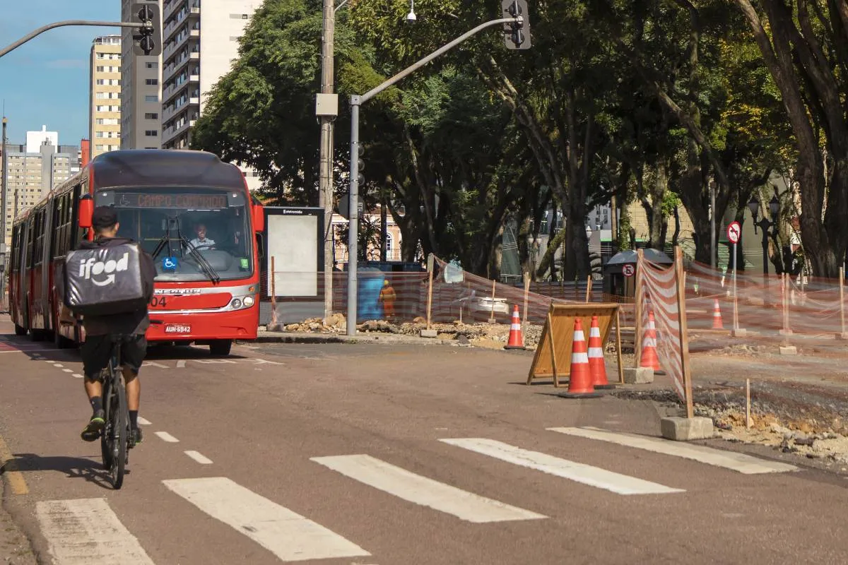 Imagem mostra um boqueio no trânsito de Curitiba, com um biarticulado e uma pessoa de bicicleta.
