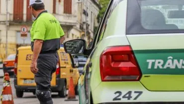 Imagem mostra uma viatura de trânsito com agentes e um carro dos correios ao fundo.