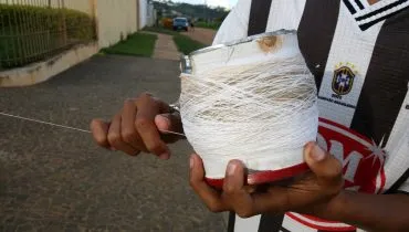 Menino enrola linha para empinar pipa.