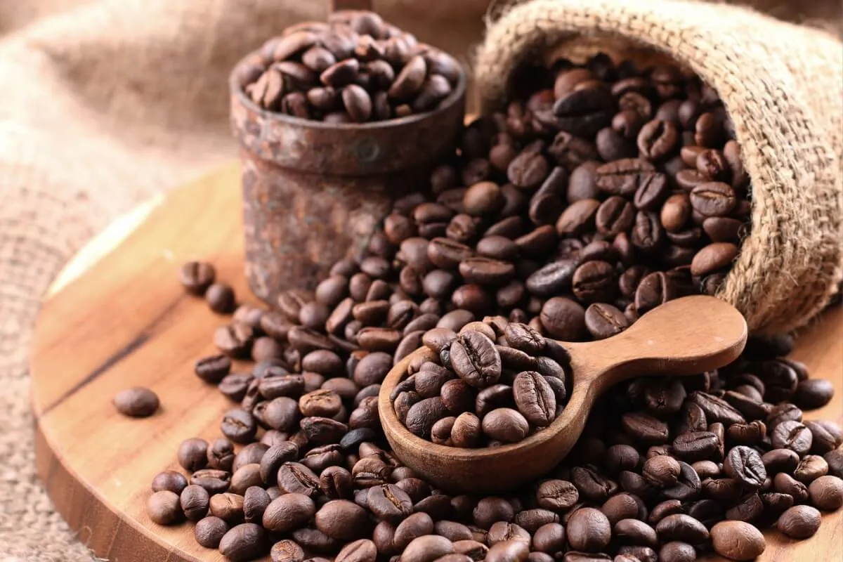 Imagem mostra grãos de café em cima de uma mesa.