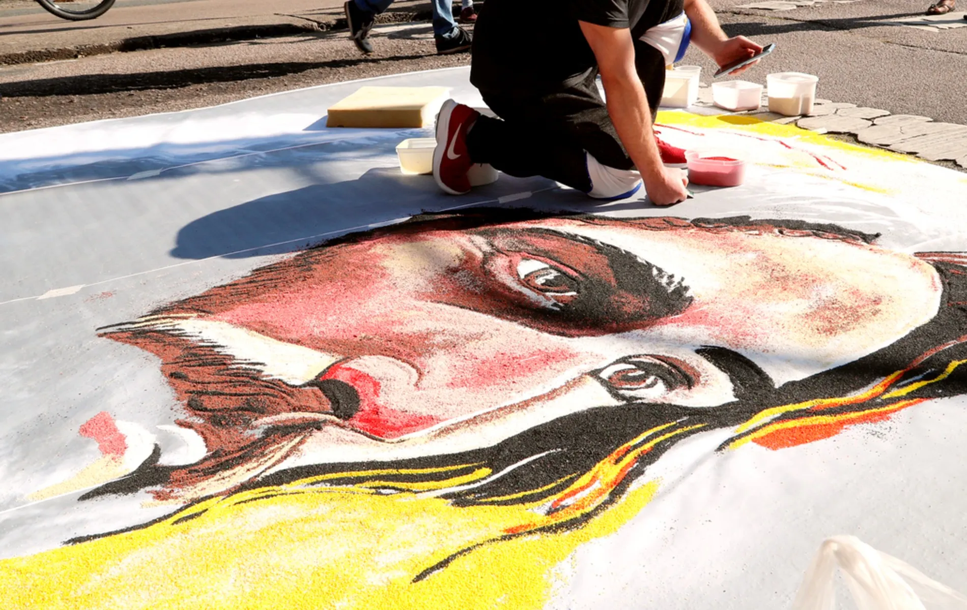 Tapete de Corpus Christi com o desenho de Cristo feito em serragem colorida.