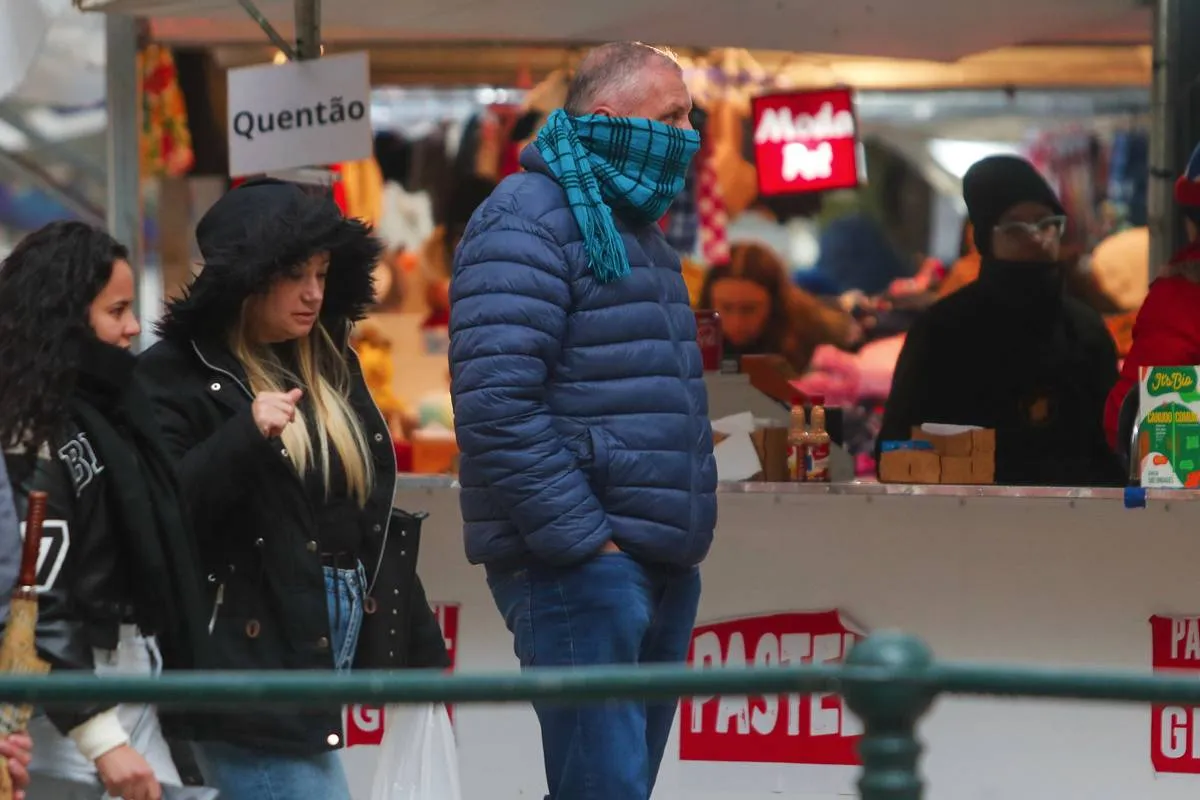 Imagem mostra pessoas com frio em uma feira de inverno.