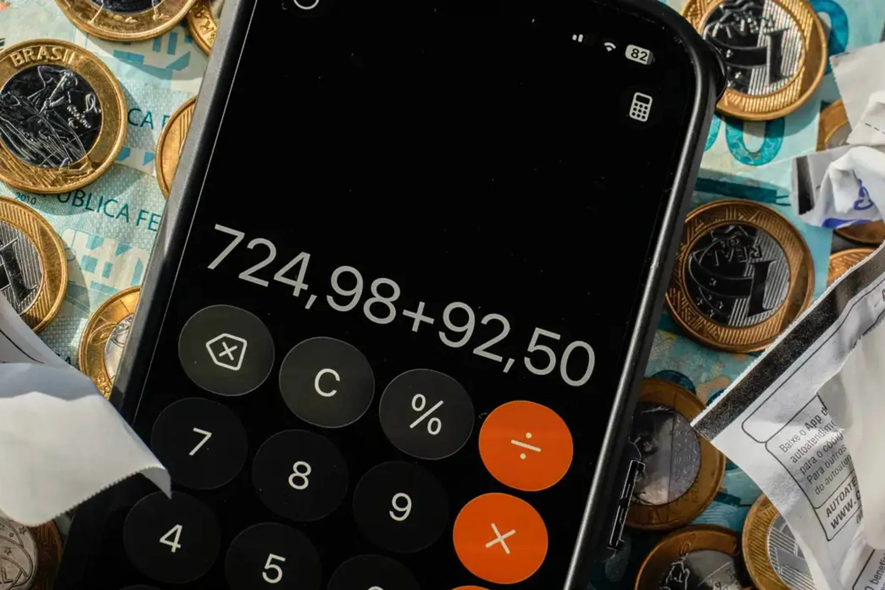 Imagem mostra uma calculadora com moedas e notas de real.
