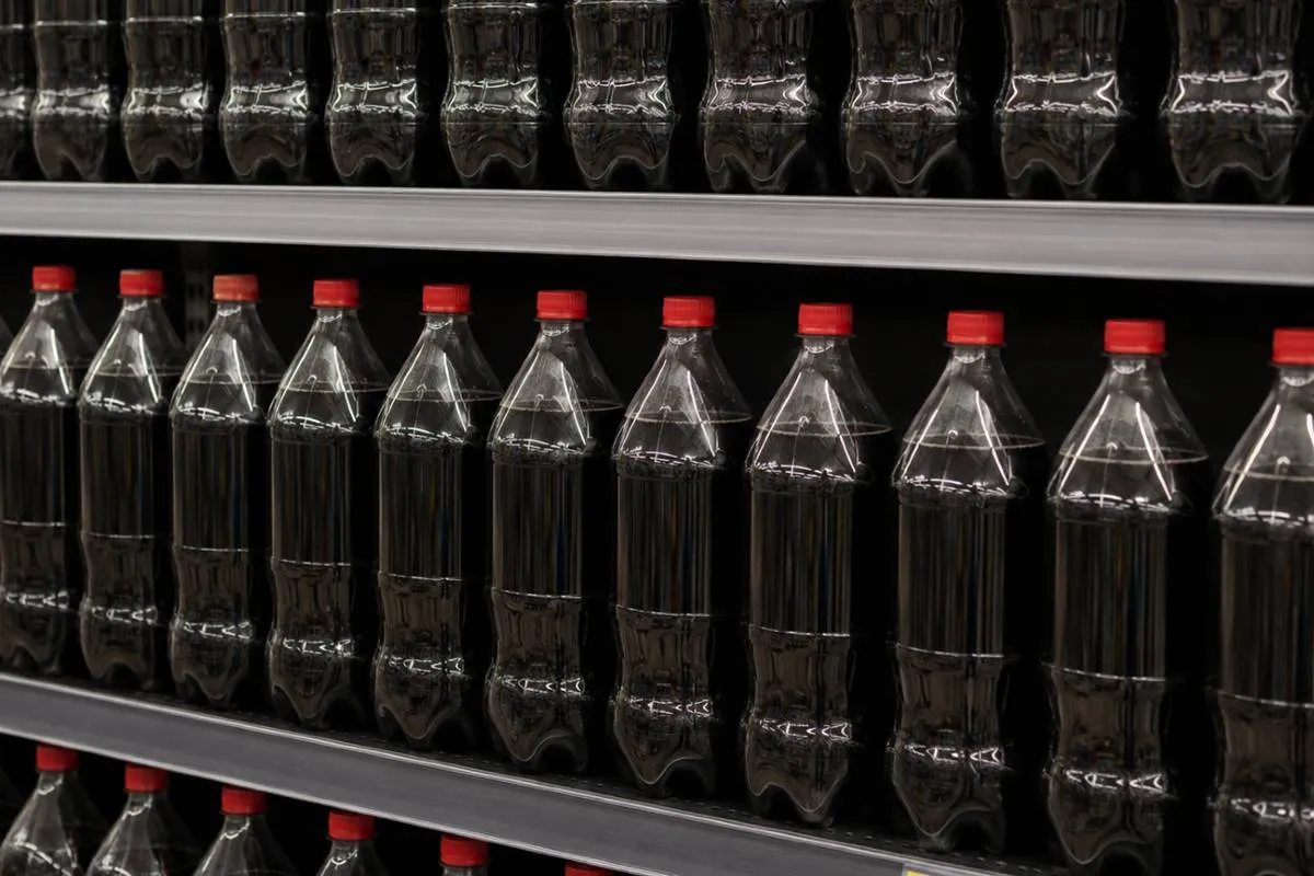 Imagem mostram garrafas de coca cola sem rótulos em uma prateleira de supermercado.