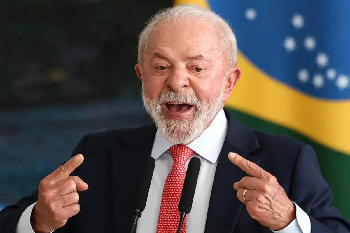 Imagem mostra Lula com a bandeira do Brasil ao fundo.