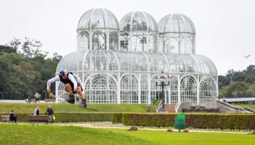 Atleta salto com um wakeboard na frente da estufa do Jardim Botânico