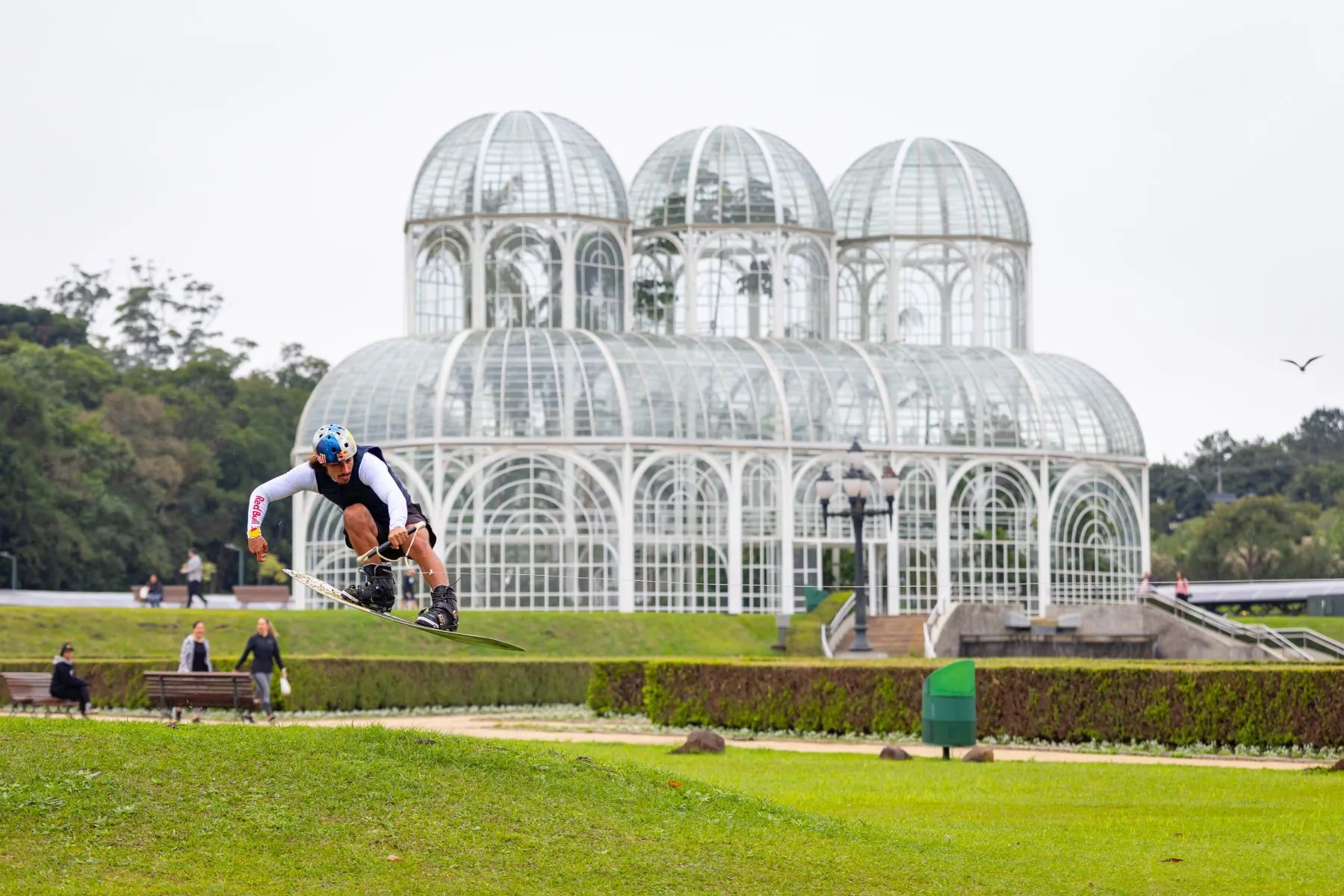Atleta salto com um wakeboard na frente da estufa do Jardim Botânico