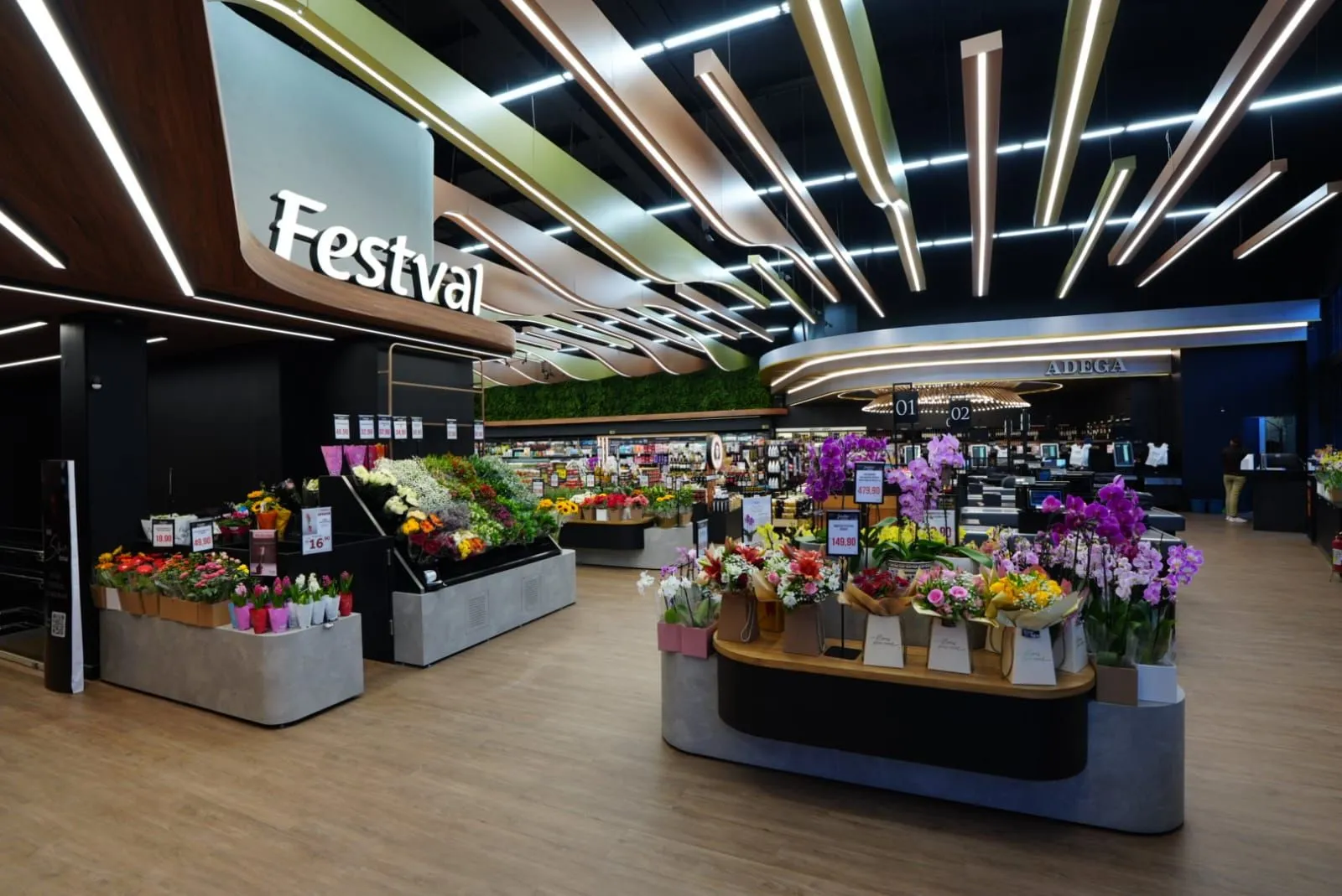 Imagem mostra o hall de entrada do supermercado, com um balcão chio de flores em primeiro plano e demais setores ao fundo