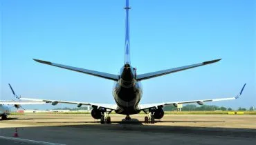 Imagem mostra um avião da Embraer modelo 195-E2 em um aeroporto. Detalhe para a parte de trás da aeronave.