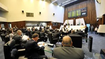 Imagem mostra plenário da Assembleia Legislativa do Paraná vista da posição dos deputados, com painel de votação e mesa diretora ao fundo