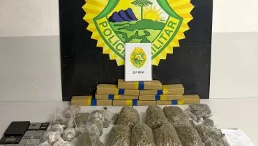Imagem mostra vários pacote de droga espalhados numa mesa, as balanças apreendidas, com um banner da Polícia Militar ao fundo