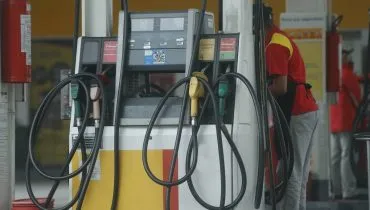 Imagem mostra um posto de combustíveis com carros abastecendo.
