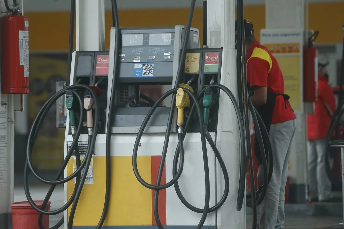 Imagem mostra um posto de combustíveis com carros abastecendo.