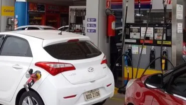 Imagem mostra um posto de combustíveis com carros abastecendo.