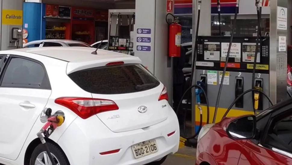 Imagem mostra um posto de combustíveis com carros abastecendo.