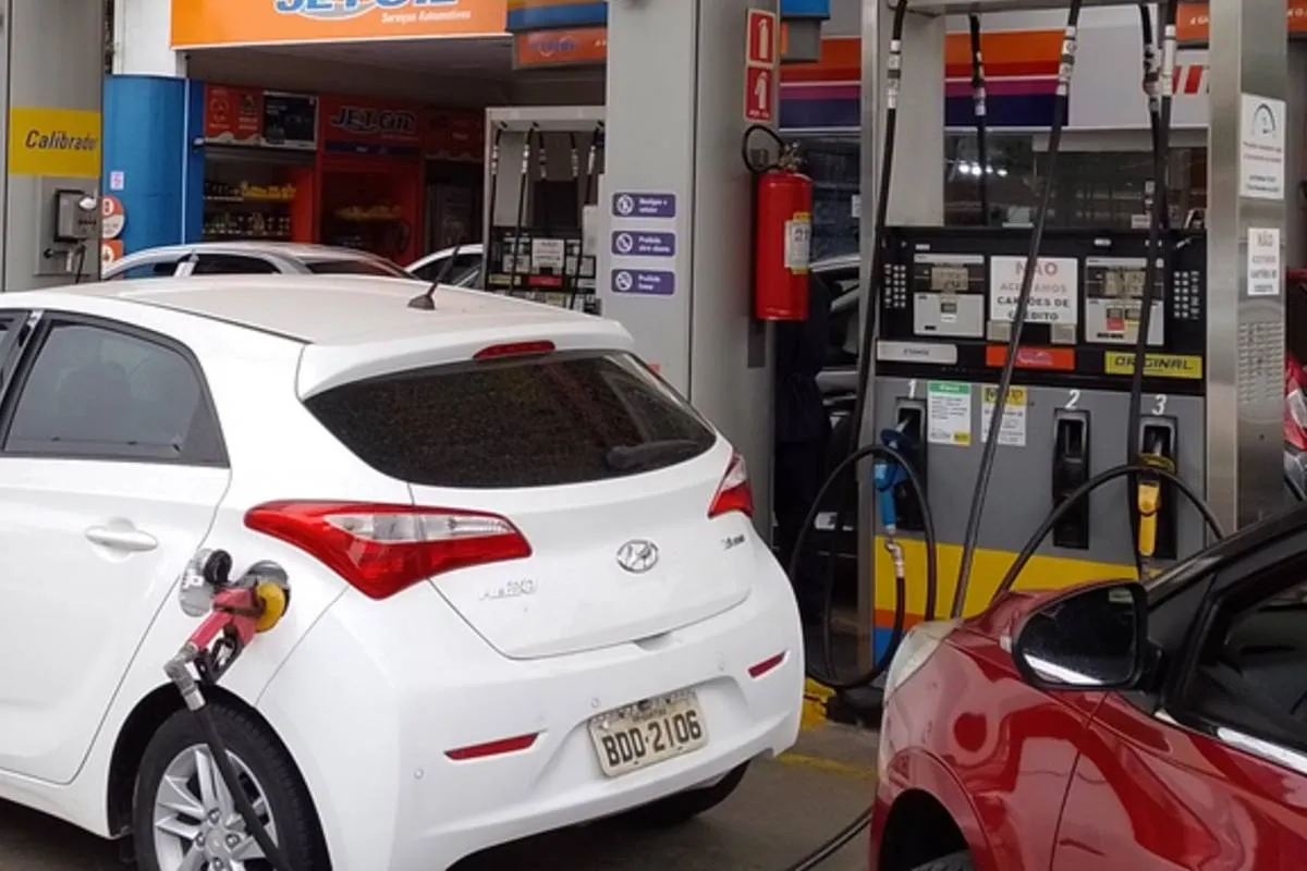 Imagem mostra um posto de combustíveis com carros abastecendo.