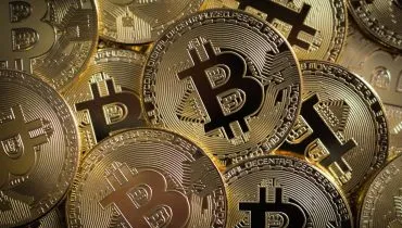 Imagem mostra a representação de criptomoedas em cima de uma mesa.