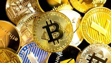 Imagem mostra a representação de criptomoedas em cima de uma mesa.