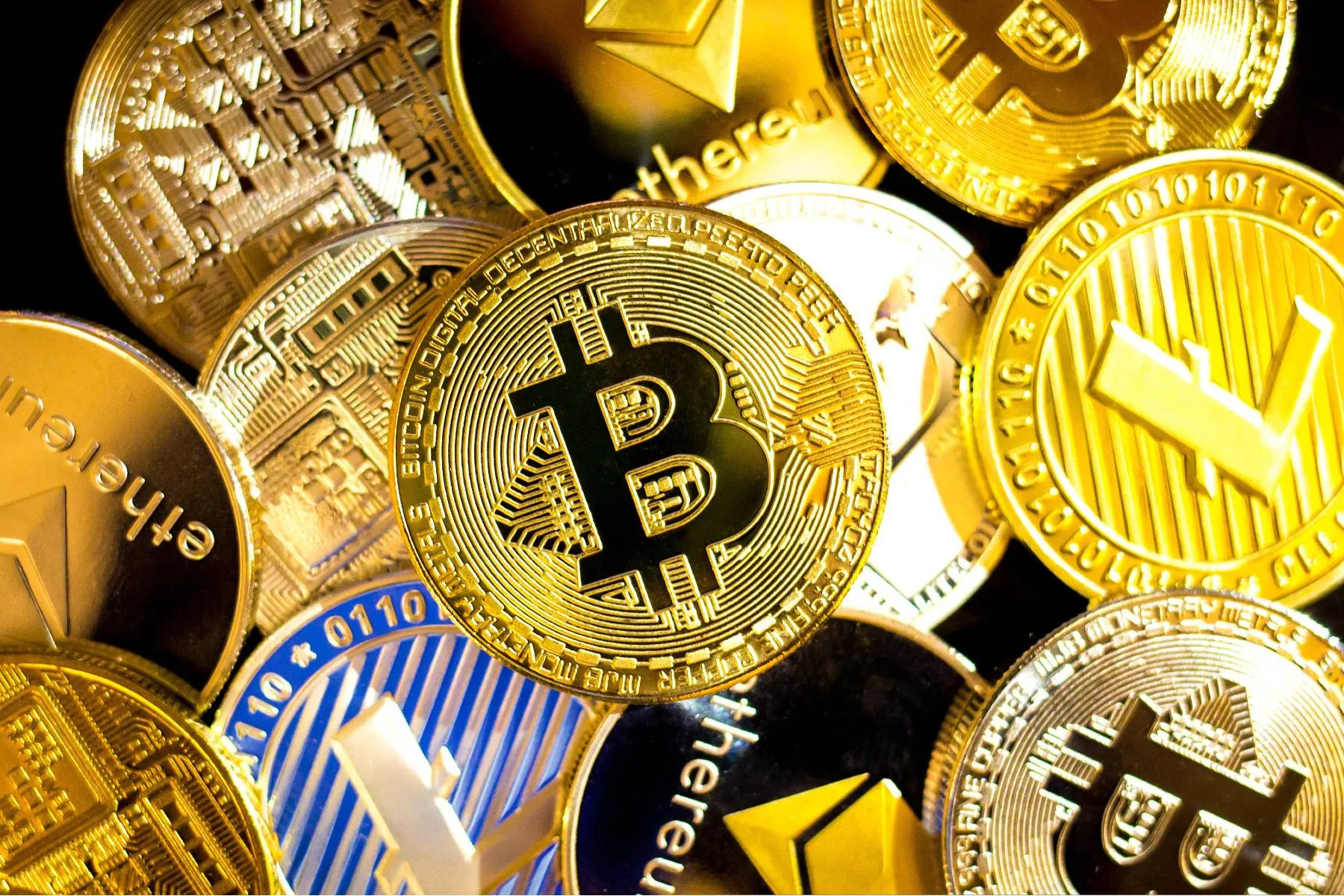 Imagem mostra a representação de criptomoedas em cima de uma mesa.