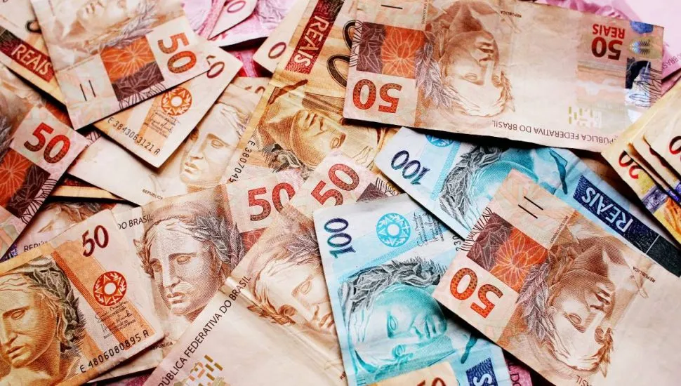Imagem mostra notas de real em cima de uma mesa.
