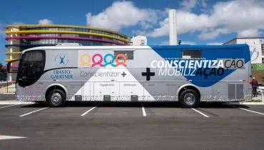Imagem mostra um Ônibus plotado com imagem de SÃo Francisco de Assis no estacionamento do Hospital Erastinho