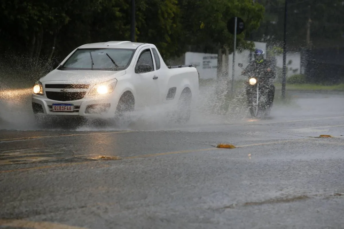 Imagem mostra um carro passando por uma rua alagada de Curitiba.