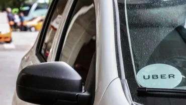 Imagem mostra um carro cinza estacionado na rodoferroviária de Curitiba. O veículo tem um adesivo escrito Uber no canto inferior esquerdo de quem vê.