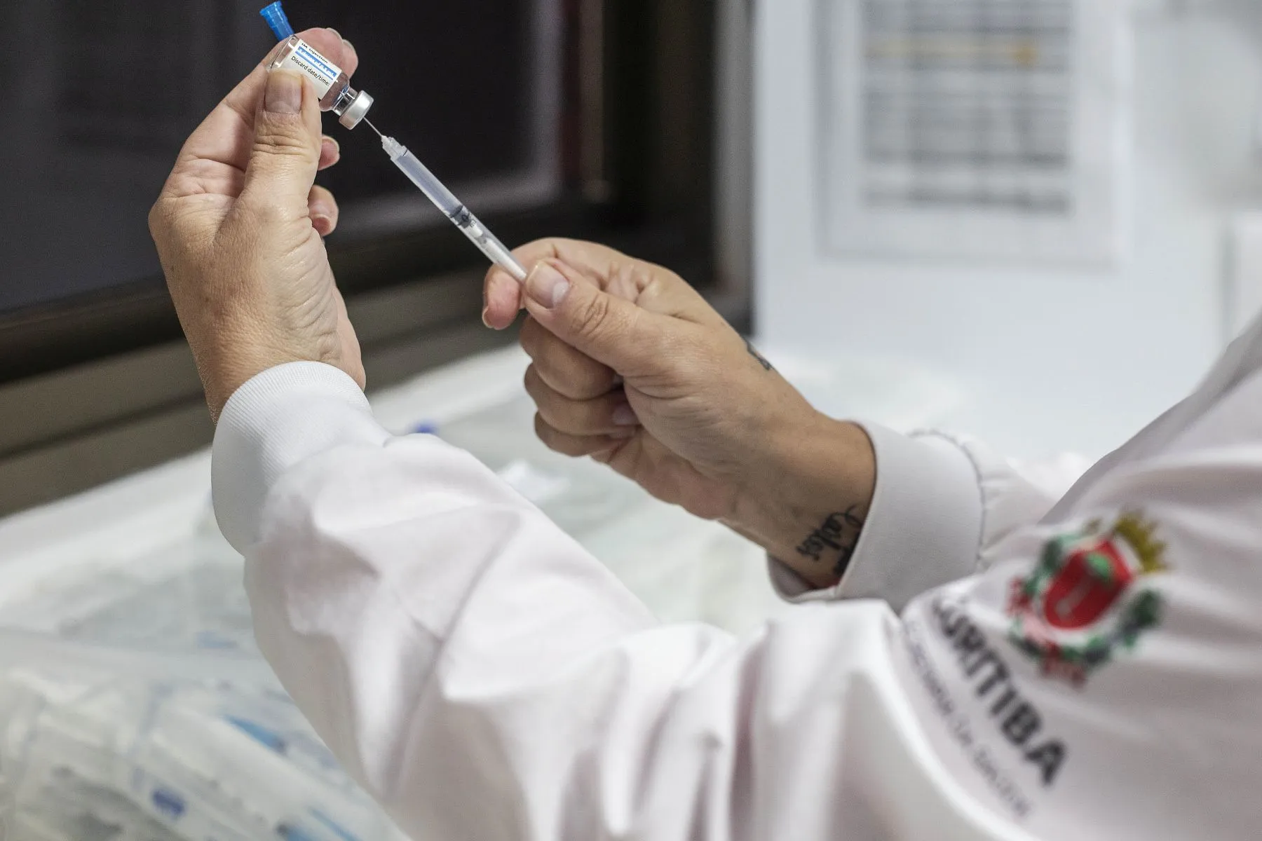 Mãos femininas seguram seringa e ampola com vacina