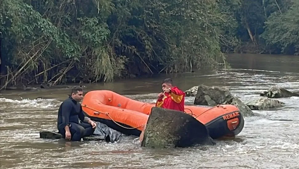 imagemmostra dois homens, um num bote, após encontrar corpo de menina preso a pedra em um rio