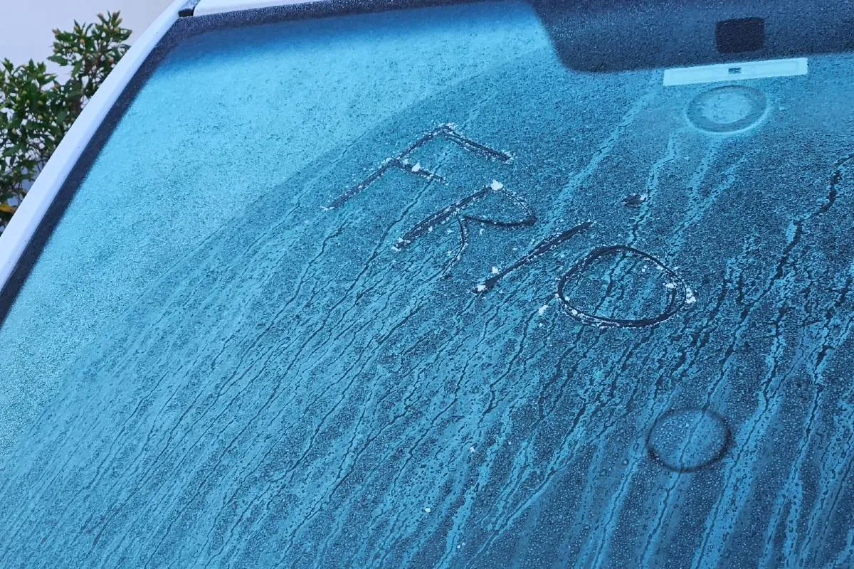 Imagem mostra o para-brisa de um carro congelado e com um escrito no gelo dizendo "Frio"
