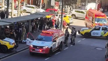imagem de cima mostra aglomeração de policiais e viaturas da polícia militar e bombeiros, além de muitos pedestres curiosos, no meio da rua e em pontos de ônibus