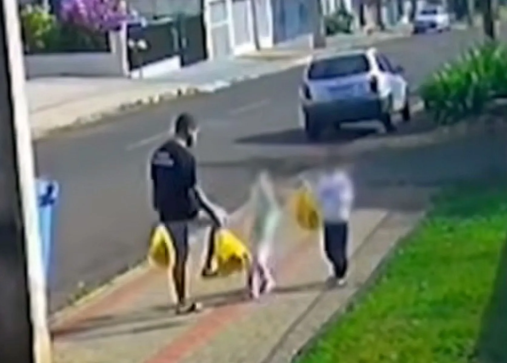 Imagem mostra homem carregado com sacolas de mercado chutando a filha, que também carregada uma sacola, ao lado do irmão