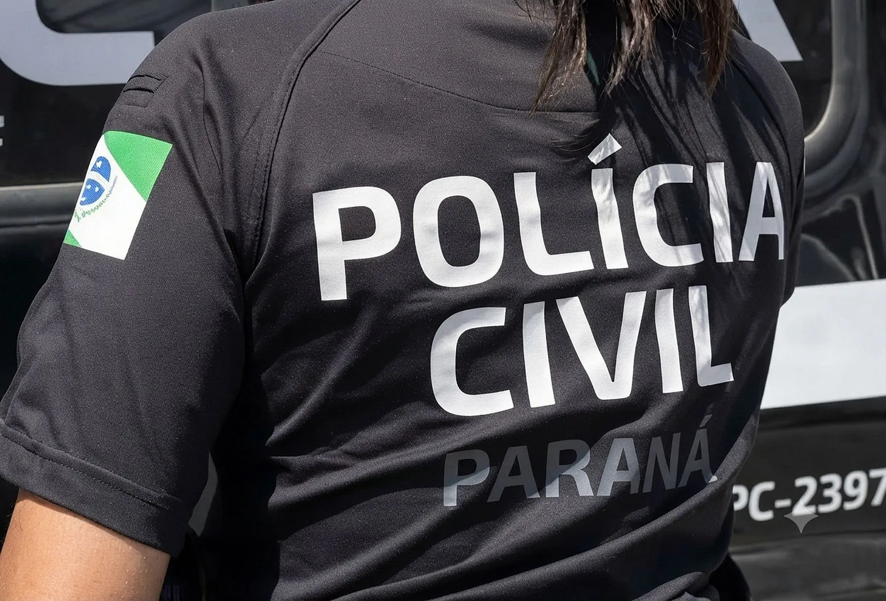 imagem mostra as costas de uma policial da Polícia Civil com uma camiseta com o nome da força de segurança