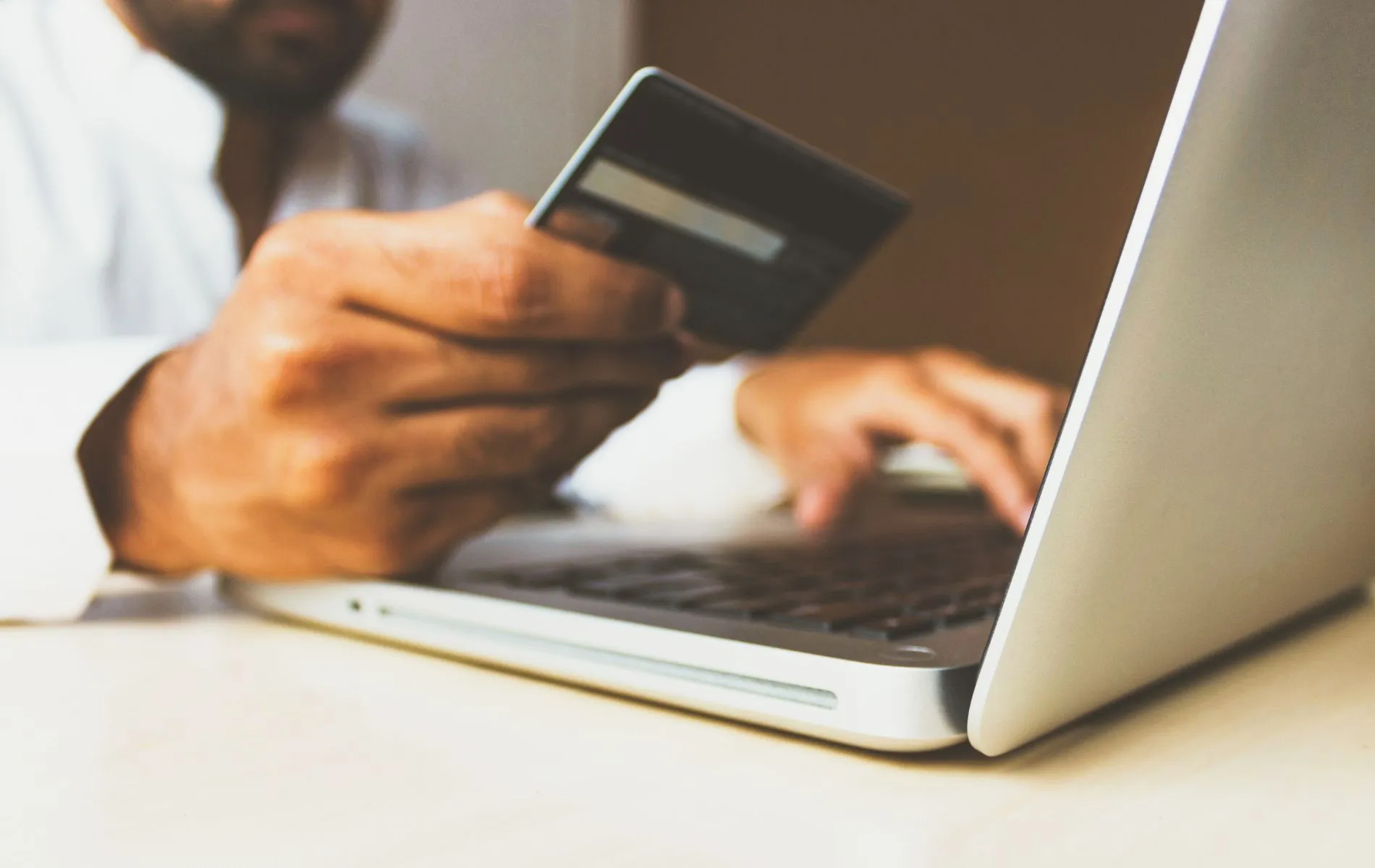 Pessoa usa o cartão de crédito e um computador