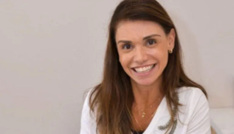 Mulher de cabelo castanho comprido, sorrindo para a câmera / primeira academia para neurodivergentes do Paraná