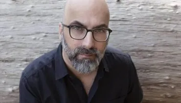 Imagem mostra um homem com careca, de óculos e com uma camisa preta.