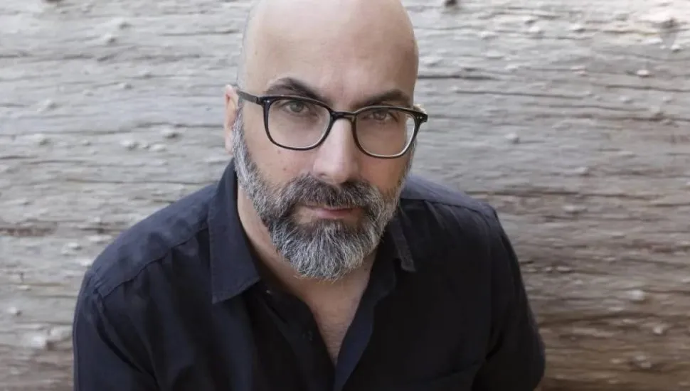 Imagem mostra um homem com careca, de óculos e com uma camisa preta.