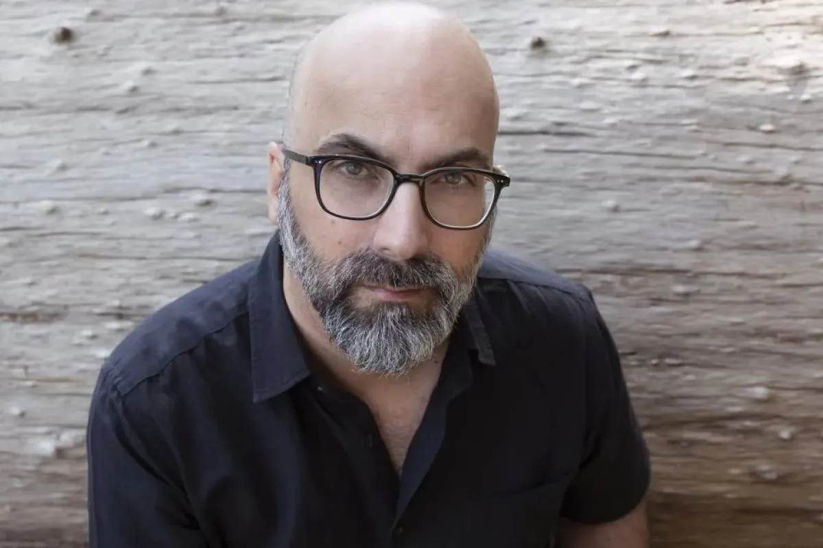 Imagem mostra um homem com careca, de óculos e com uma camisa preta.