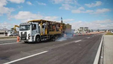 Imagem mostra um caminhão pintando as faixas das pistas do novo viaduto de Curitiba.